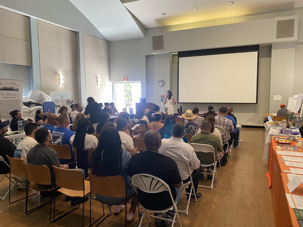 a woman in a white dress speaking in front of an audience in a seminar style room